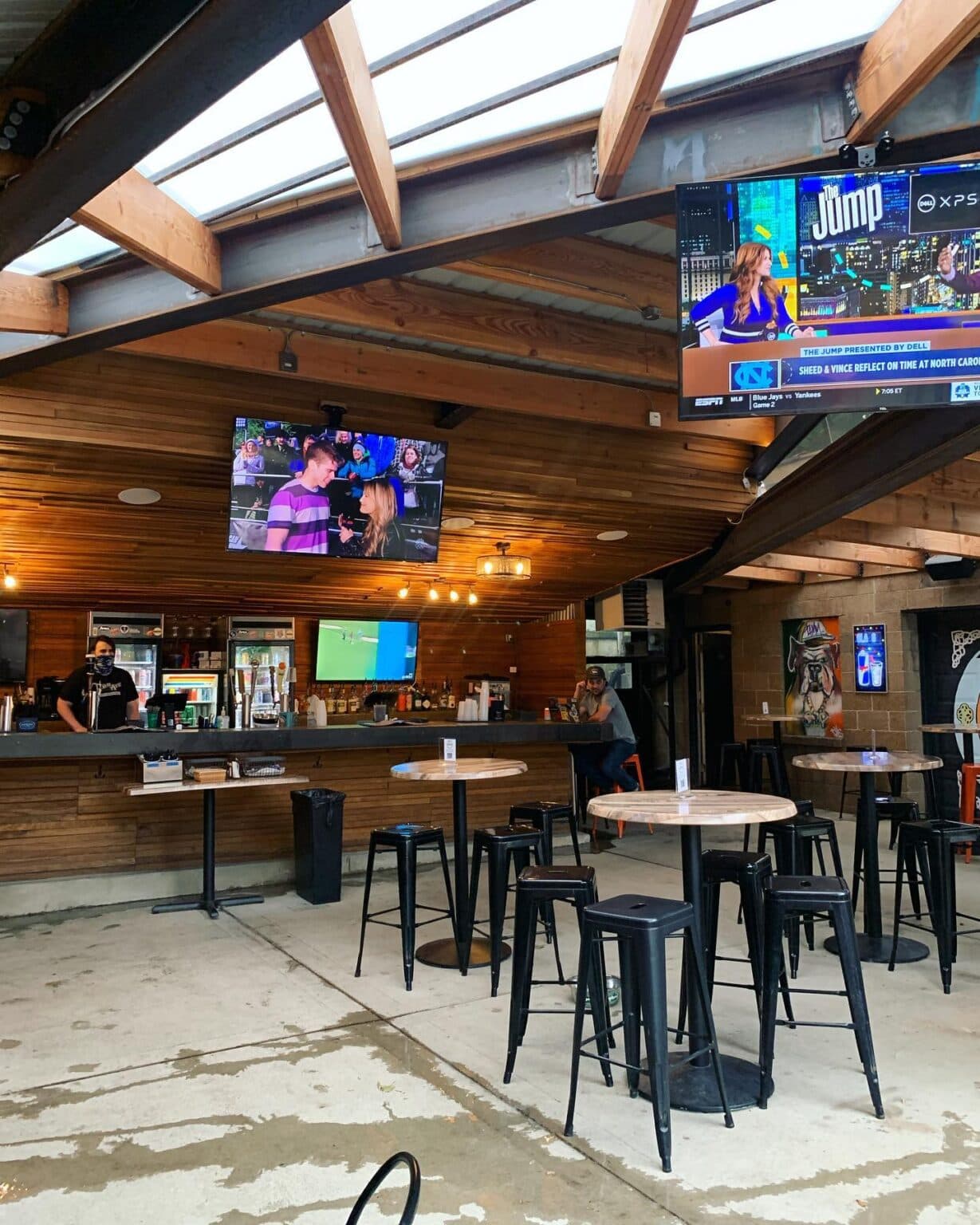 The covered patio: wooden bar, TVs, and high-top tables