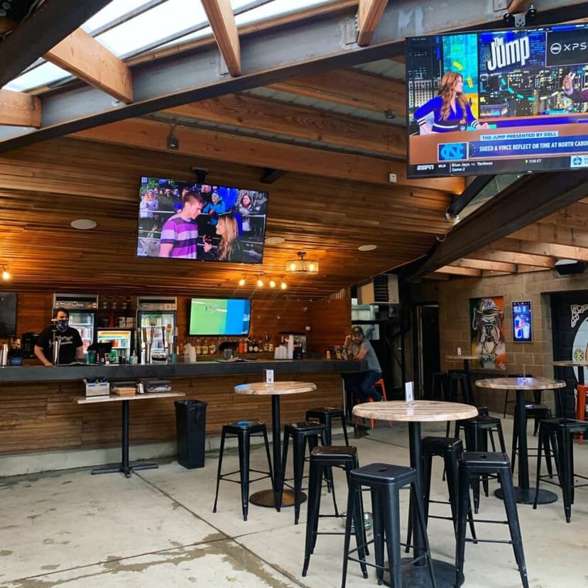 The covered patio with its wooden bar, TVs, and high-top tables