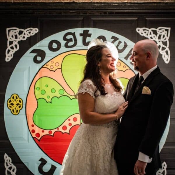 Bride and groom laughing in front of the Dogtown United mural